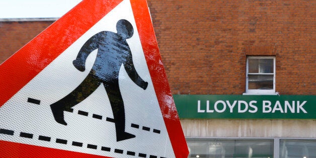 A pedestrian sign stands near a branch of Lloyds Bank in London, Tuesday, Oct. 28, 2014. The State-backed Lloyds Banking Group is to cut 9,000 jobs over the next three years as part of plans which will see the closure of some high street branches in a bid to improve efficiency, it is announced Tuesday.(AP Photo/Kirsty Wigglesworth)