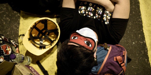 HONG KONG - OCTOBER 20: A pro-democracy protester sleeps inside a barricade at Mong Kok on October 20, 2014 in Hong Kong, Hong Kong. Expected clashes between pro-democracy protesters and the police did not occure, as Fernando Cheung (not pictured), a member of the parliament and vice-chairman of the Labour Party showed up at protesters barricades and calmed down the intense situation. Hong Kong's Chief Executive Leung Chun-ying has set talks for October 21 between protest groups and government