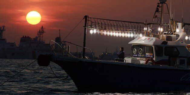 A man stands on a fishing boat using its lights to help illuminate an area of recovery operations at the site of the submerged 'Seowl' ferry off the coast of the South Korean island of Jindo on April 24, 2014. The confirmed death toll from South Korea's ferry disaster rose sharply to more than 120 on April 22, as divers speeded up the grim task of recovering bodies from the submerged ship and police took two more of its crew into custody. AFP PHOTO/ Nicolas ASFOURI (Photo credit should r