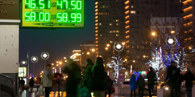 Pedestrians pass illuminated rates for dollar and euro currencies against the ruble on an electronic sign outside a currency exchange bureau near residential apartment blocks in Moscow, Russia, on Sunday, Nov. 9, 2014. The ruble has lost more than 28 percent against the dollar so far this year, the second-worst performance among more than 170 currencies tracked by Bloomberg. Photographer: Andrey Rudakov/Bloomberg via Getty Images
