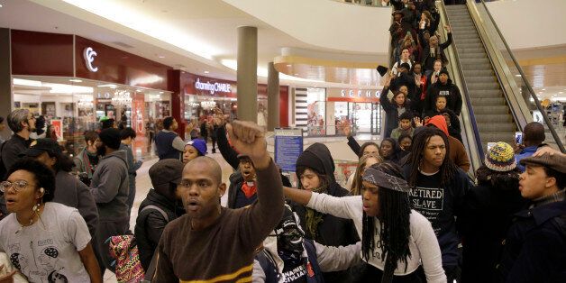 Protesters march inside Chesterfield Mall Friday, Nov. 28, 2014, in Chesterfield, Mo. The crowd disrupted holiday shopping at several locations on Friday amid a protest triggered by a grand jury's decision not to indict the police officer who fatally shot Michael Brown in nearby Ferguson. (AP Photo/Jeff Roberson)