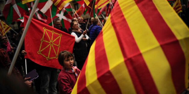 EDS NOTE : SPANISH LAW REQUIRES THAT THE FACES OF MINORS ARE MASKED IN PUBLICATIONS WITHIN SPAIN. Pro-independence demonstrators of Catalonia and Basque Country raise their regional flags as they gather on a square to support an informal independence poll to celebrate Catalonia, in Pamplona northern Spain, Sunday, Nov. 9, 2014. The pro-independence regional government of Catalonia stages a symbolic poll on secession in a show of determination and defiance after the Constitutional Court suspended its plans to hold an official independence referendum following a legal challenge by the Spanish government. (AP Photo/Alvaro Barrientos)