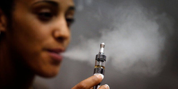 Kathleene, an electronic cigarette store employee, smokes an electronic cigarette in Paris, Tuesday, Oct. 8, 2013. The European Parliament voted to impose warning labels covering 65 percent of cigarette packs, rejecting a measure for blank packaging instead. Legislators also voted for new limits on advertising for electronic cigarettes, but rejected a measure that would have restricted them to medical use only. (AP Photo/Christophe Ena)