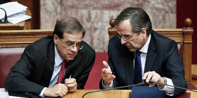 Greek Prime minister Antonis Samaras, right, chats with Greece's Finance Minister Gikas Hardouvelis during a debate on a confidence vote demanded by the conservative-led governing coalition half-way through its four-year mandate, in Athens on Friday, Oct. 10, 2014. Prime Minister Antonis Samarasâ government is expected to win the vote, but it faces possible early elections soon as it will need opposition support to elect Greeceâs new president in March. (AP Photo/Petros Giannakouris)