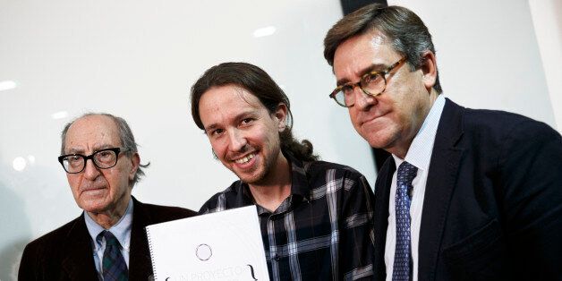 Pablo Iglesias, Secretary General of 'Podemos' ('We can'), center, poses as he holds 'An Economic Project for the People' written by Spanish economists Vincenc Navarro, left, and Juan Torres, right, in Madrid, Spain, Thursday, Nov. 27, 2014. Latest polls show the recently-formed Spanish party 'Podemos' has risen to become the most popular choice among Spanish voters for the general elections to be held in 2015. (AP Photo/Daniel Ochoa de Olza)