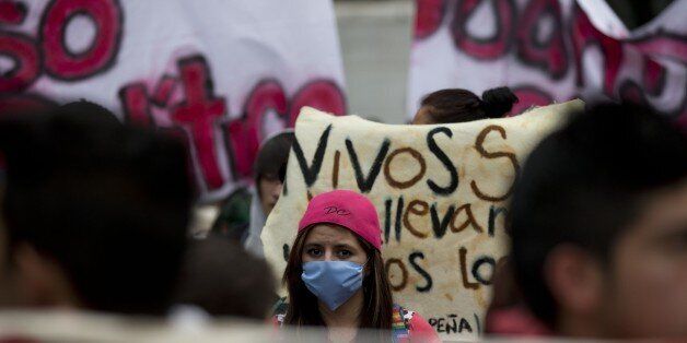 A protestor covers her face as she walks during a protest demanding the release of students detained during a massive protest on Nov. 20, 2014, in Mexico City, Tuesday, Nov. 25, 2014. Tens of thousands marched to the capital's main plaza last week, demanding that authorities find 43 missing college students. The march ended in violence when the demonstrators clashed with police and scores where detained and arrested. (AP Photo/Rebecca Blackwell)