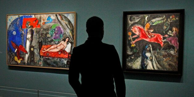 A member of the media views a painting by Russian artist Marc Chagall before the opening of the exhibition: Chagall, between War and Peace, at the Luxembourg museum in Paris, Tuesday Feb. 19, 2013. The exhibition starts February 21 and ends July 21, 2013. Painting at right is: 1944, Le Cheval Rouge, and at left: 1944, A Ma Femme.(AP Photo/Remy de la Mauviniere)
