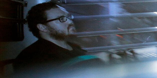 In this photo taken through a tinted glass, Rurik George Caton Jutting, a 29-years-old British banker, sitting in a prison bus arrives at a court in Hong Kong Monday, Nov. 24, 2014. The British banker is in his trial over the deaths of two Indonesian women he is suspected of killing. (AP Photo/Vincent Yu)
