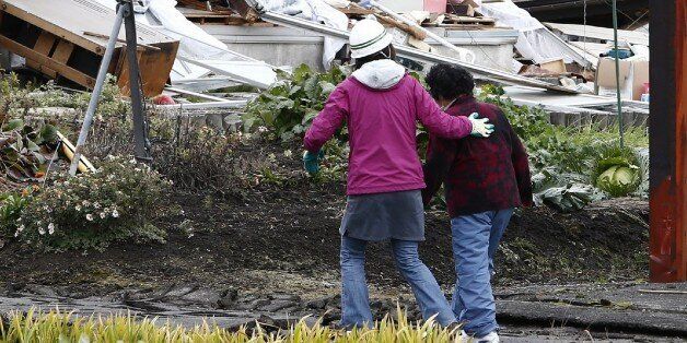 Local residents walk past a collapsed house after a strong earthquake hit the area the night before, in Hakuba, some 300 kms northwest of Tokyo, Nagano prefecture, on November 23, 2014. A strong 6.2 magnitude earthquake, which hit late on November 22 in central Japan, left 39 people injured, seven seriously, and wrecked homes in a popular ski resort. JAPAN OUT AFP PHOTO/Jiji Press (Photo credit should read JIJI PRESS/AFP/Getty Images)