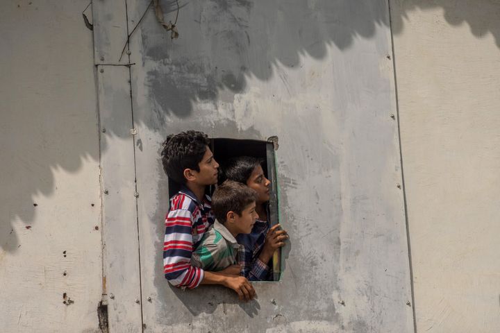 Kashmiri children look towards clashes between protesters and security forces on August 30, 2019. TheJammu and Kashmir Police has been arresting children without paper trails that could hold them accountable.