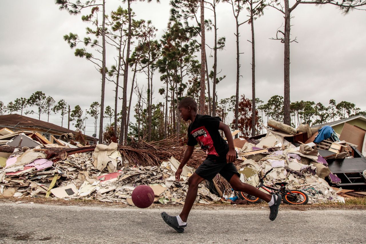 A boy dribbles a ball through debris caused by Hurricane Dorian in Freeport, Grand Bahama Sept. 21, 2019.