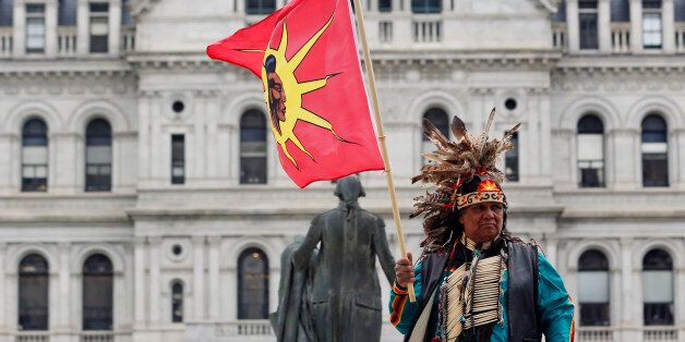 Thomas Square from the Akwesasne territory in northern New York holds a flag during an Earth Day rally outside the Capitol on Wednesday, April 22, 2015, in Albany, N.Y. (AP Photo/Mike Groll)