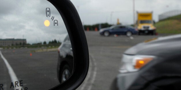 In this photo taken, Tuesday, May 22, 2012, professional test driver J.D. Ellis of Cincinnati, Ohio, demonstrates the side mirror warning signal in a Ford Taurus at an automobile testing area in Oxon Hill, Md. The display at a recent transportation conference was a peek into the future of automotive safety: cars that to talk to each other and warn drivers of impending collisions. Later this summer, the government is launching a yearlong, real-world test involving nearly 3,000 cars, trucks and bu
