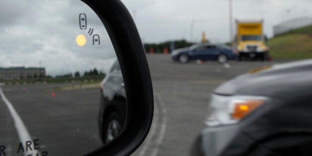 In this photo taken, Tuesday, May 22, 2012, professional test driver J.D. Ellis of Cincinnati, Ohio, demonstrates the side mirror warning signal in a Ford Taurus at an automobile testing area in Oxon Hill, Md. The display at a recent transportation conference was a peek into the future of automotive safety: cars that to talk to each other and warn drivers of impending collisions. Later this summer, the government is launching a yearlong, real-world test involving nearly 3,000 cars, trucks and bu