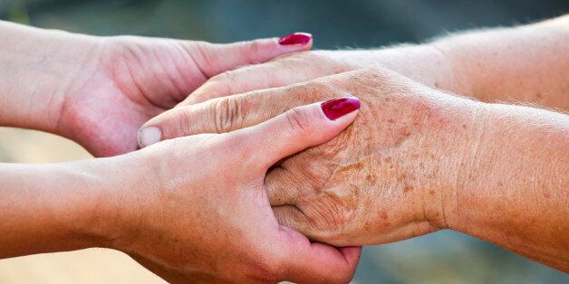 'Close-up of young adult giving senior woman her hands and helping, selective focus.'
