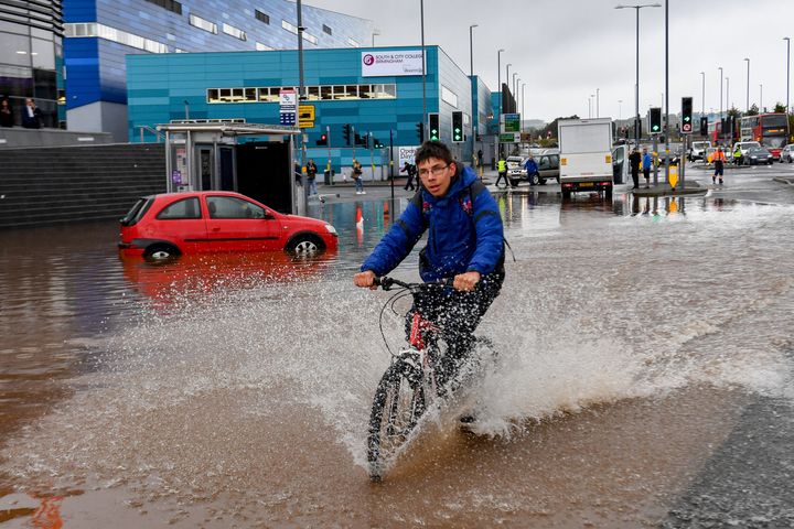 A man cycles through a flooded road in Birmingham city centre. The Met Office has issued a yellow weather warning for much of England and Wales today, with flooding expected in some areas.