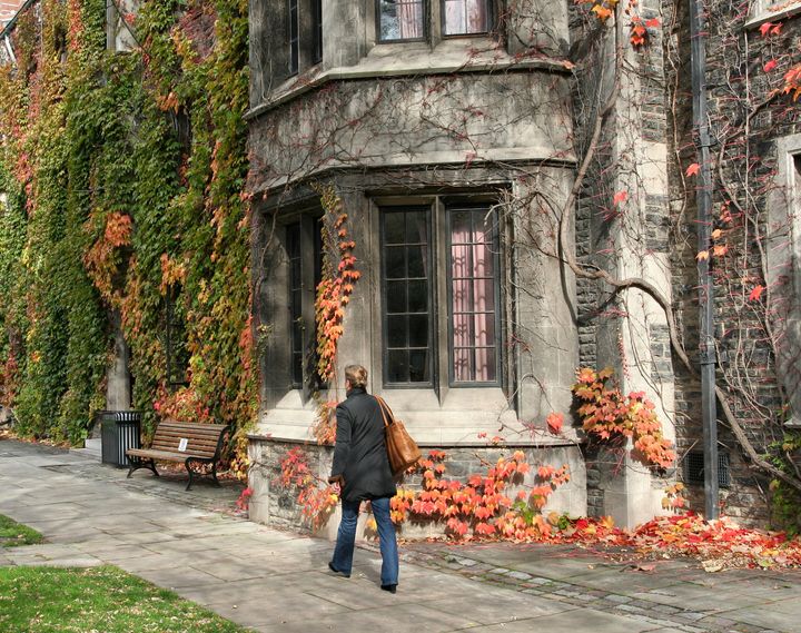 An students walks past an old college building at the University of Toronto.