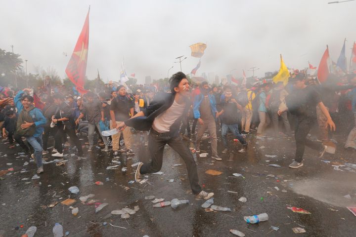 Student protesters are sprayed with a police water cannon truck during a protest outside the parliament in Jakarta, Indonesia