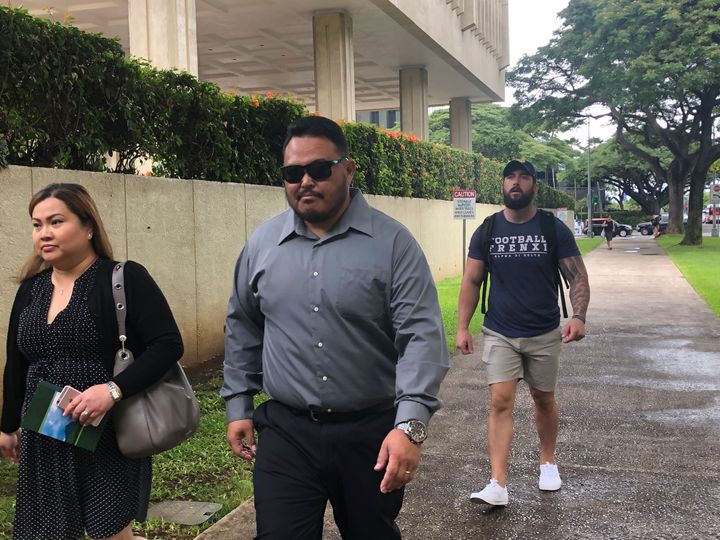 Former Honolulu police officer Reginald Ramones, center, walks down a street in Honolulu on Wednesday, Sept. 25, 2019. Ramones has pleaded guilty to failing to report that another police officer forced a homeless man to lick a public urinal. (AP Photo/Jennifer Sinco Kelleher)