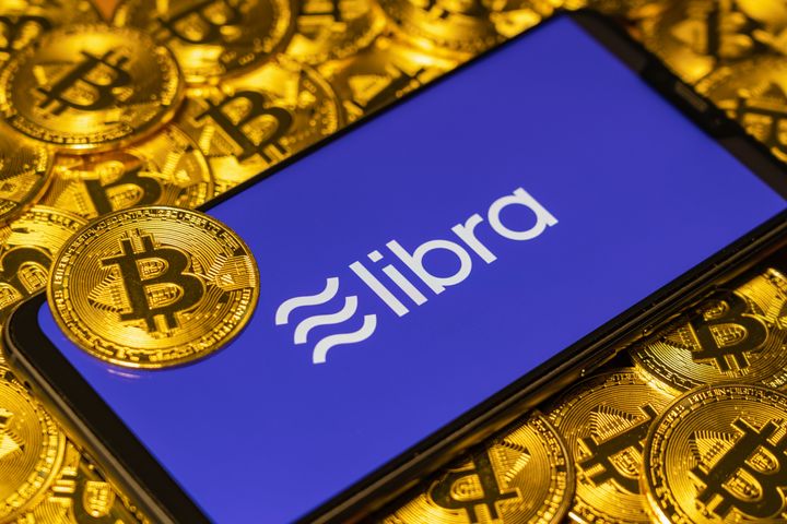 Gold Bitcoin Coins pile with the Facebook's Libra Crypto Coin logo on smartphone screen（仮想通貨のイメージ写真）