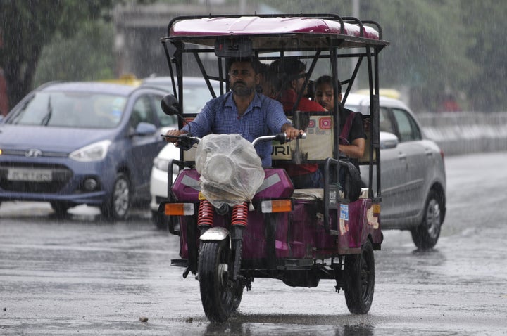 An e-rickshaw and vehicles during rain in Noida.