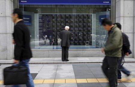 Man looks at a stock quotation board outside a brokerage in Tokyo