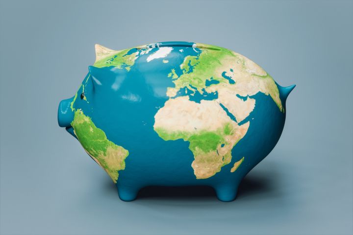World map textured piggy bank on pale blue background.