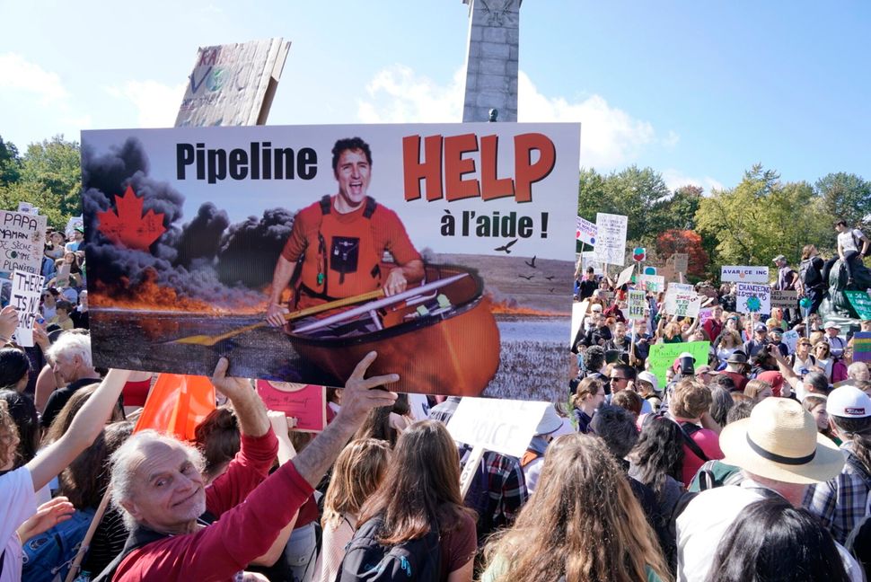 A demonstrator holds a photo of Liberal Leader Justin Trudeau in a canoe surrounded by smoke and fire at a climate protest in Montreal on Sept. 27, 2019.