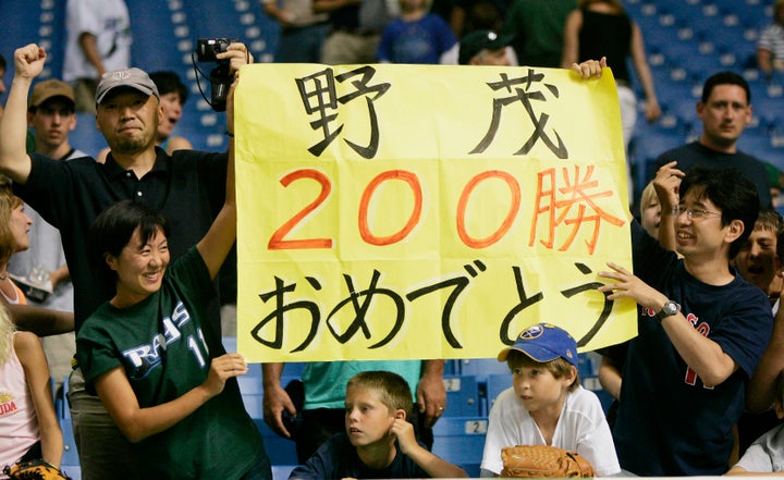 Fans hold up signs congratulating Tampa Bay Devil Rays pitcher Hideo Nomo on his 200th victory at Tropicana Field in St. Pete