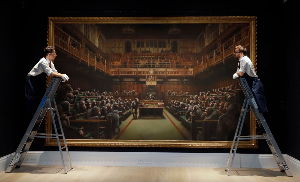 Υπάλληλοι του οίκου Sotheby κοιτάζουν τον πίνακα του καλλιτέχνη Bansky που βρίσκεται εκτεθειμένο σε αίθουσα δημοπρασιών του οίκου στο Λονδίνο, την Παρασκευή.