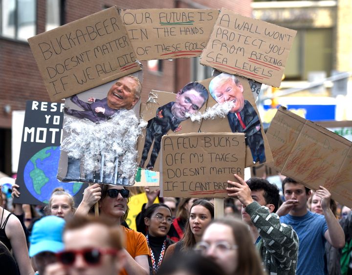 People hold signs depicting Ontario Premier Doug Ford, Conservative leader Andrew Scheer and U.S. President Donald Trump as they march in Ottawa as part of a Global Climate Strike, protesting against climate change and inaction on Sept. 27, 2019. 