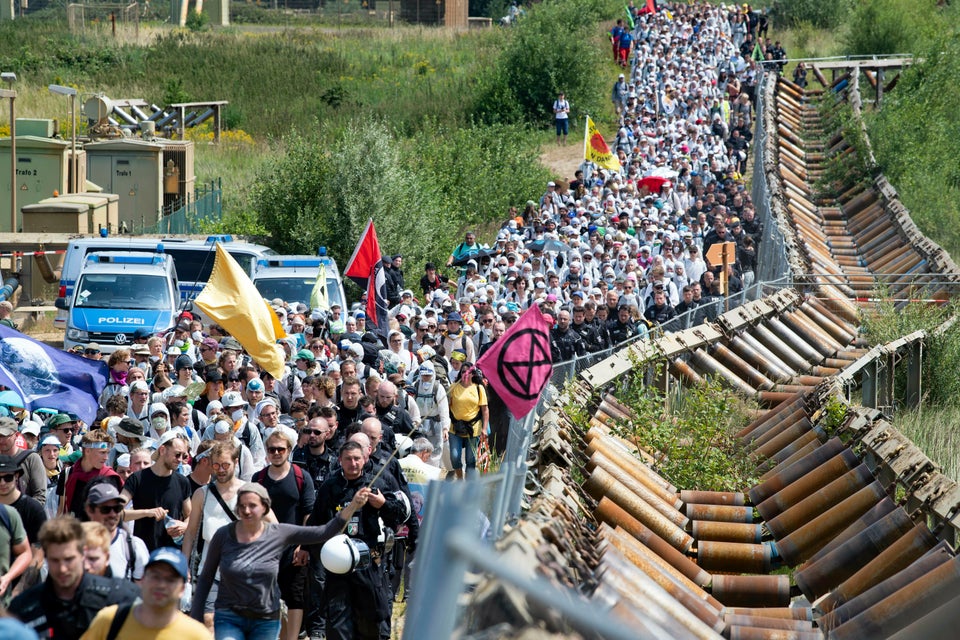 Numerous environmental activists walk on a roadway on the site of the Garzweiler open-cast mine in Garzweiler, Germany, Saturday, June 22, 2019. The protests for more climate protection in the Rhineland continue. (Marcel Kusch/dpa via AP)