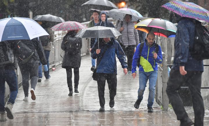 Pedestrians try to shelter from the rain under umbrellas in Bristol