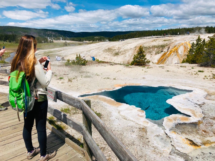 A woman takes photos of Blue Star spring near Old Faithful Upper Geyser Basin in Yellowstone National Park.