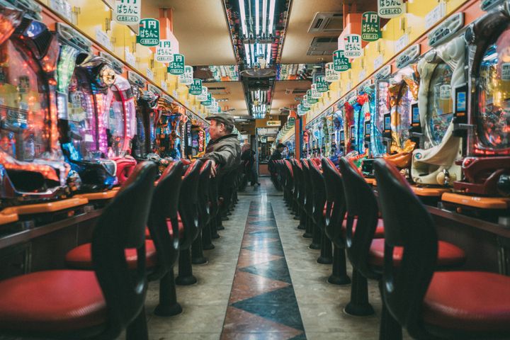 Osaka, Japan, November 22nd 2018: Lonely man sitting in front of Pachinko Gambling Machine. Shot from public street into Pachinko Parlor. Vanishing point of view into the Pachinko Gambling Parlor. Shinsekai, Osaka, Japan, Asia.