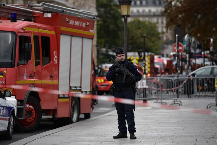 A policeman stands next to firefighter vehicles near where four officers were killed in a knife attack.