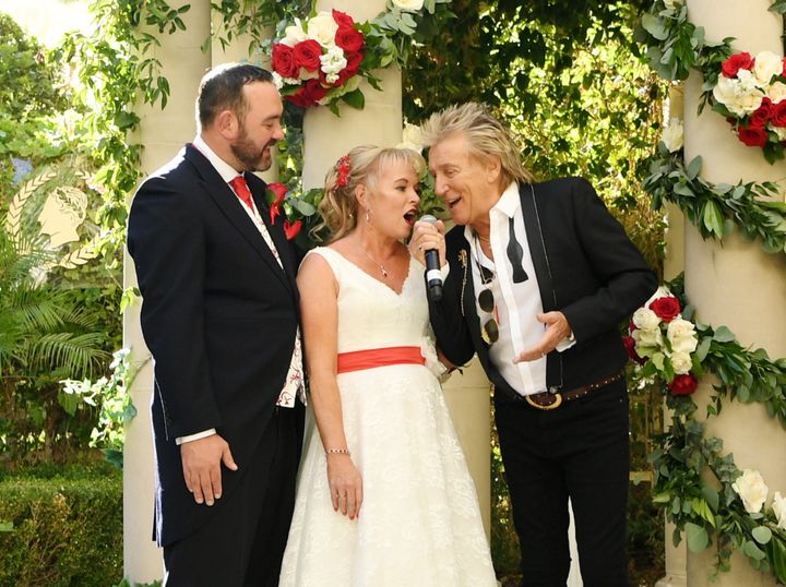 Rod Stewart and bride Sharon Cook sing while groom Andrew Aitchison looks on in delight.
