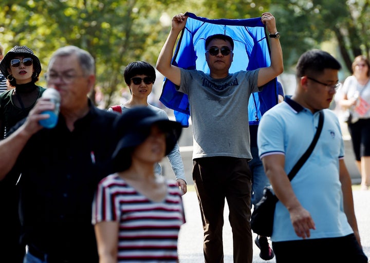 A tourist visiting the Lincoln Memorial shields himself from the sun as temperatures are expected to soar into mid-90s, on October 2, 2019 in Washington, DC.