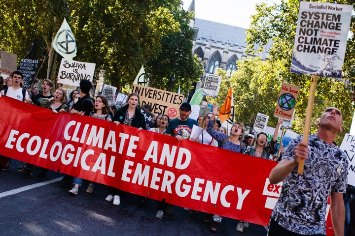 Extinction Rebellion activists group hold a banner and placards at a climate strike in London 