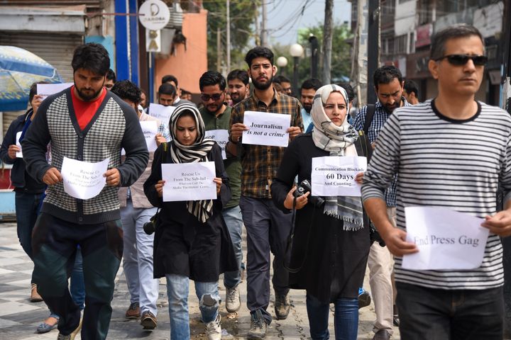 Journalists hold placards while marching during the protest. 