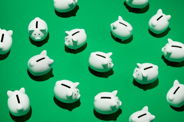 16 small white piggy banks placed randomly on green surface, high angle of