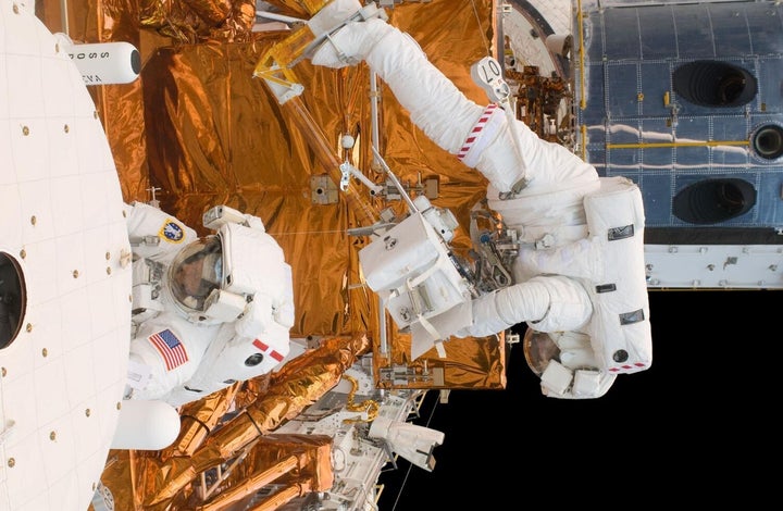 Astronauts Michael Good and Mike Massimino (l-r) work on the Hubble Space Telescope