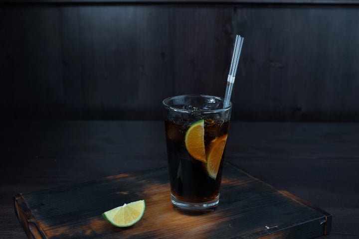 Alcoholic tasty cocktail with the addition of ice, whiskey and Coca-Cola, lime slices stands on a wooden table in the restaurant. The original serving of drinks in the bar.