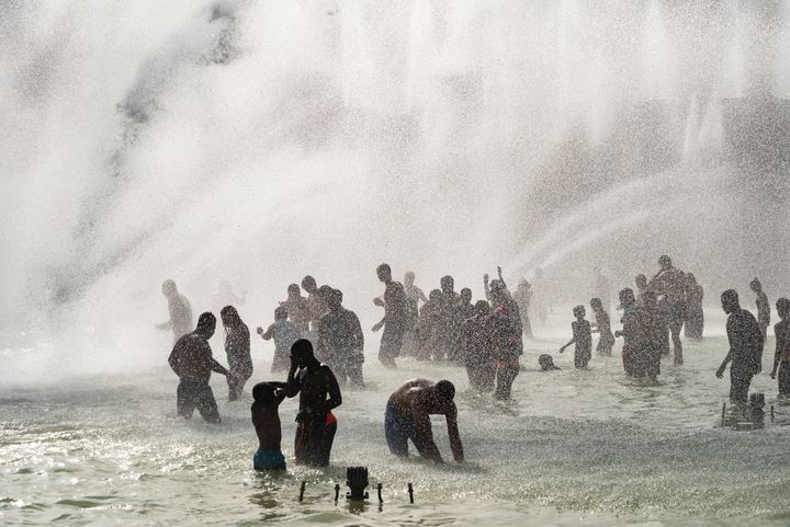 Parisians bathe under the many fountains of the Trocadero fountain to cool down as Paris experiences its highest ever recorded temperature. 