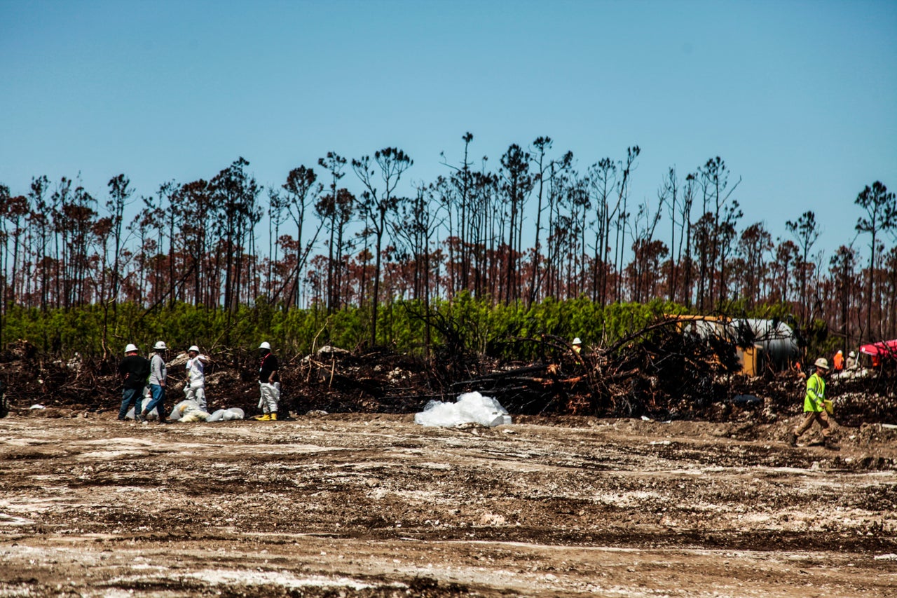 Workers clean up oil-covered debris.