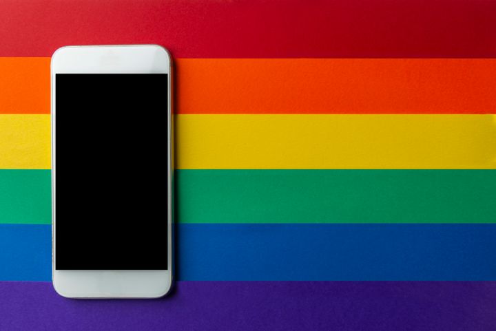 Black screen mobile phone on the multicolour LGBT background.