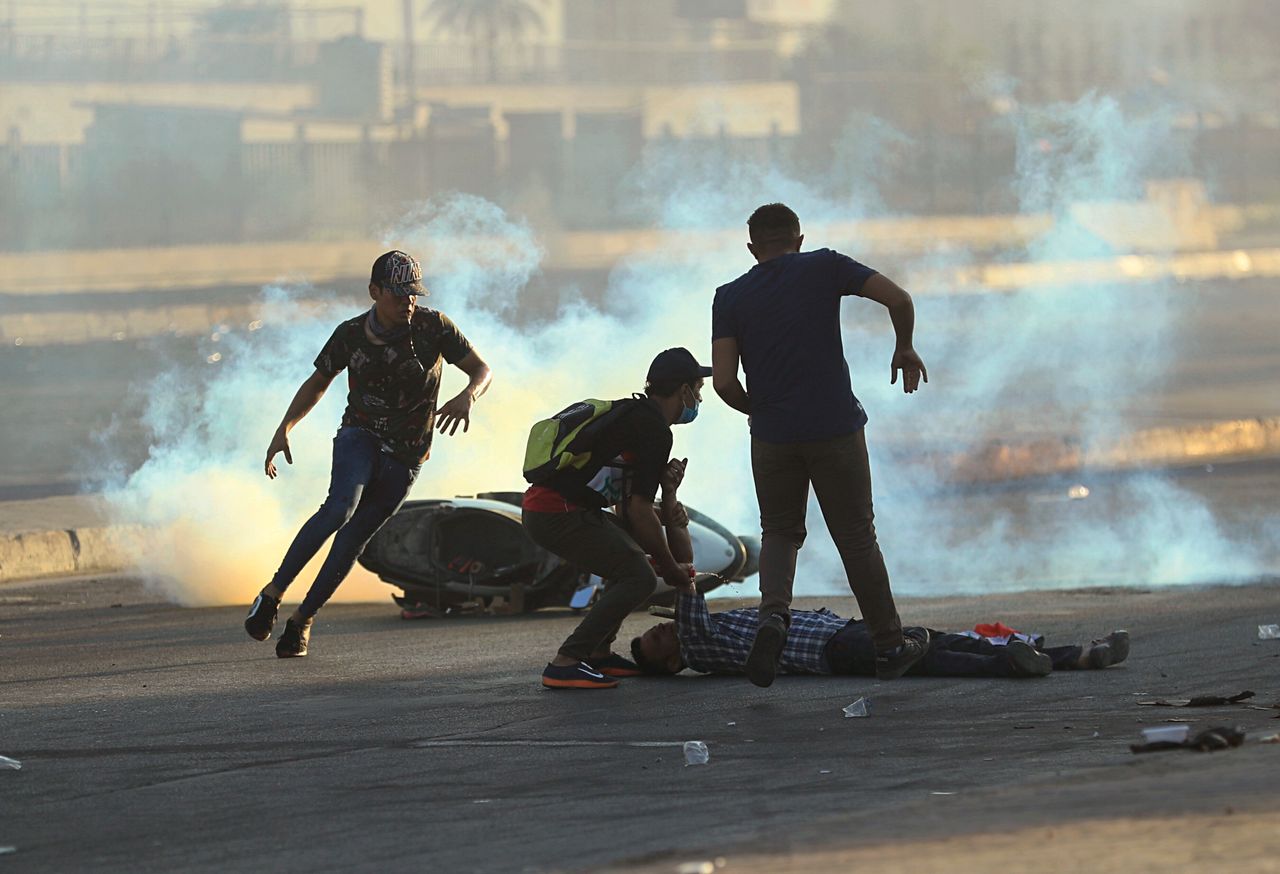 Anti-government protesters rush to an injured protestor during a demonstration in Baghdad, Iraq, Saturday.