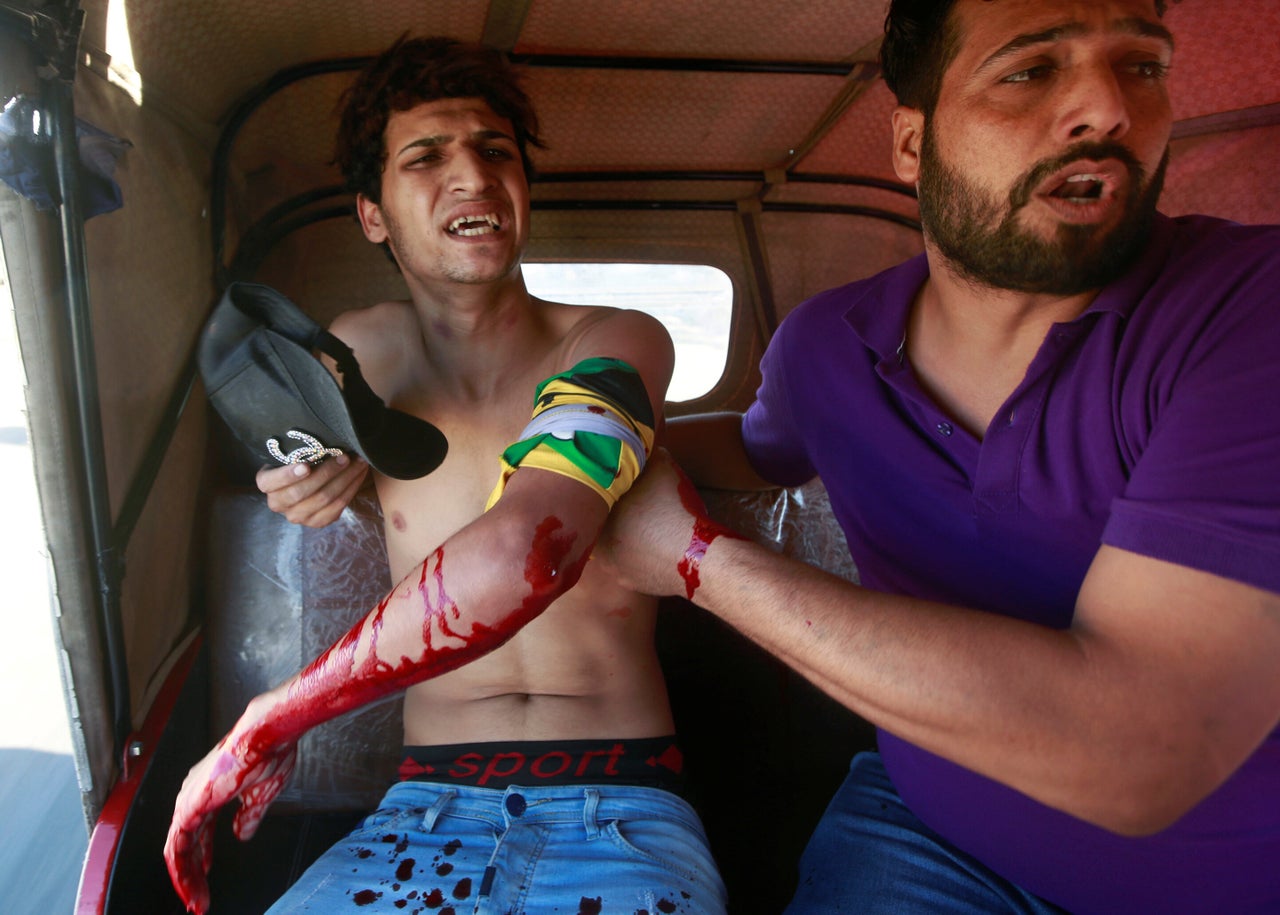 <strong> A man is seen assisting an injured demonstrator at a protest during a curfew, three days after the nationwide anti-government protests turned violent, in Baghdad, Iraq October 4.</strong>