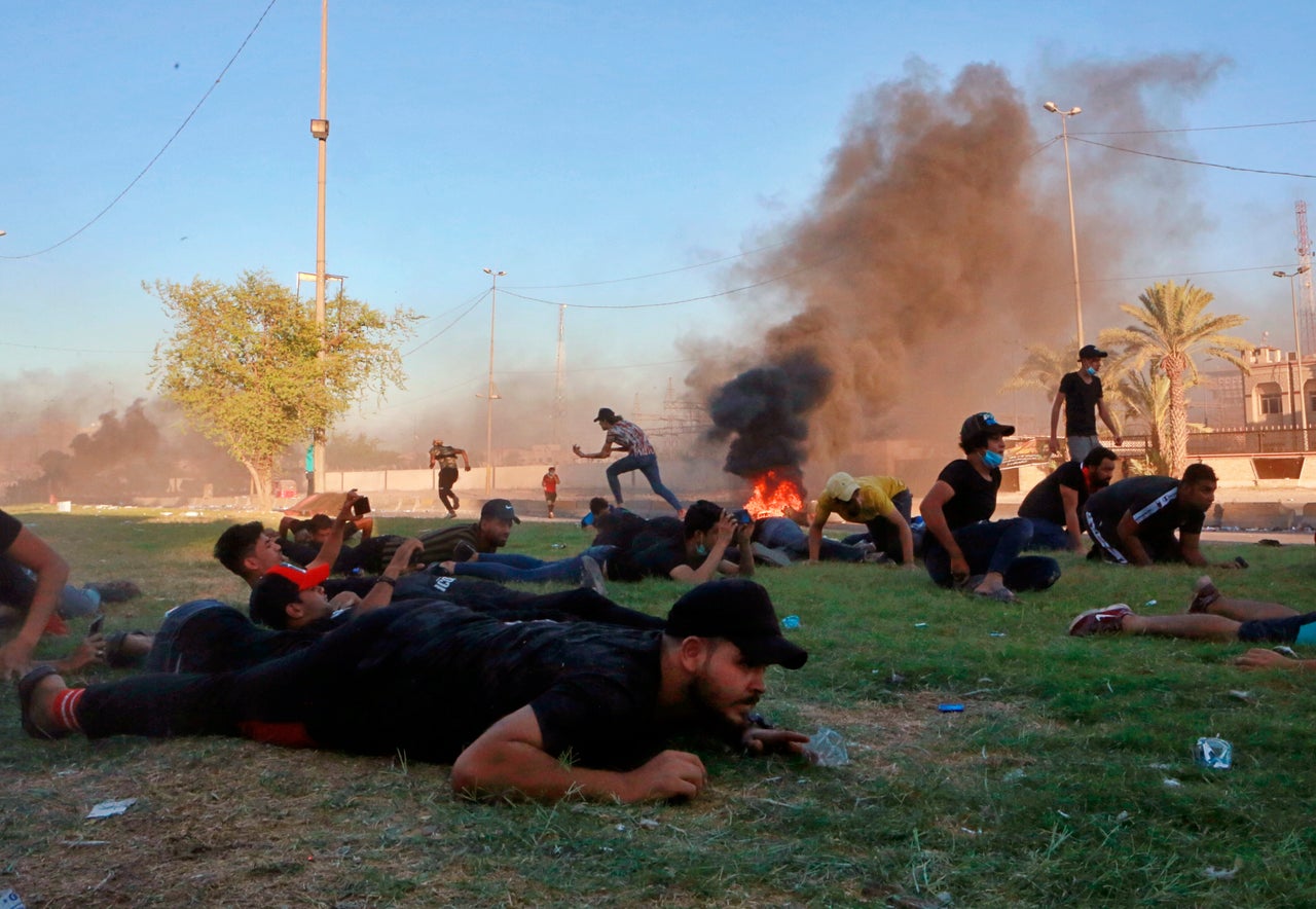 Anti-government protesters take cover while Iraq security forces fire during a demonstration in Baghdad, Iraq, Friday, Oct. 4, 2019. Security forces opened fire directly at hundreds of anti-government demonstrators in central Baghdad, killing several protesters and injuring dozens, hours after Iraq's top Shiite cleric warned both sides to end four days of violence "before it's too late." (AP Photo/Khalid Mohammed)