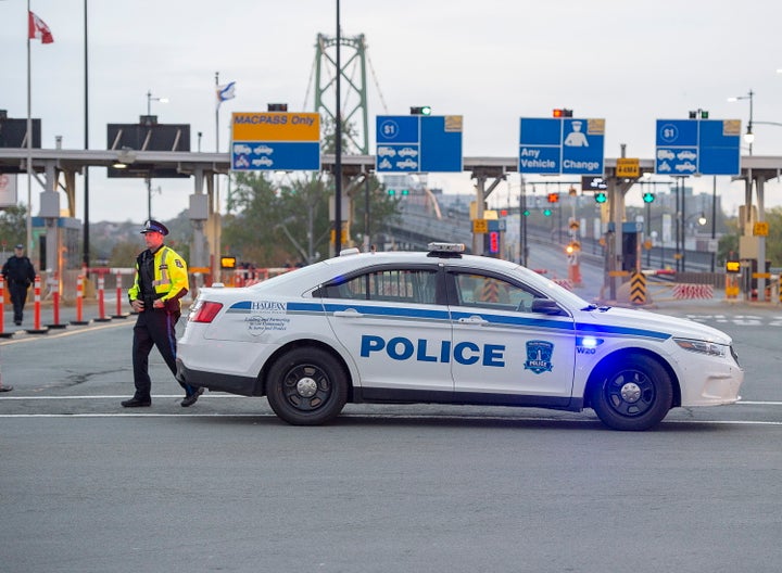 A Halifax police officer walks beside his vehicle at the Angus L. Macdonald Bridge in preparation for the climate protests planned for Monday in several Canadian cities. 